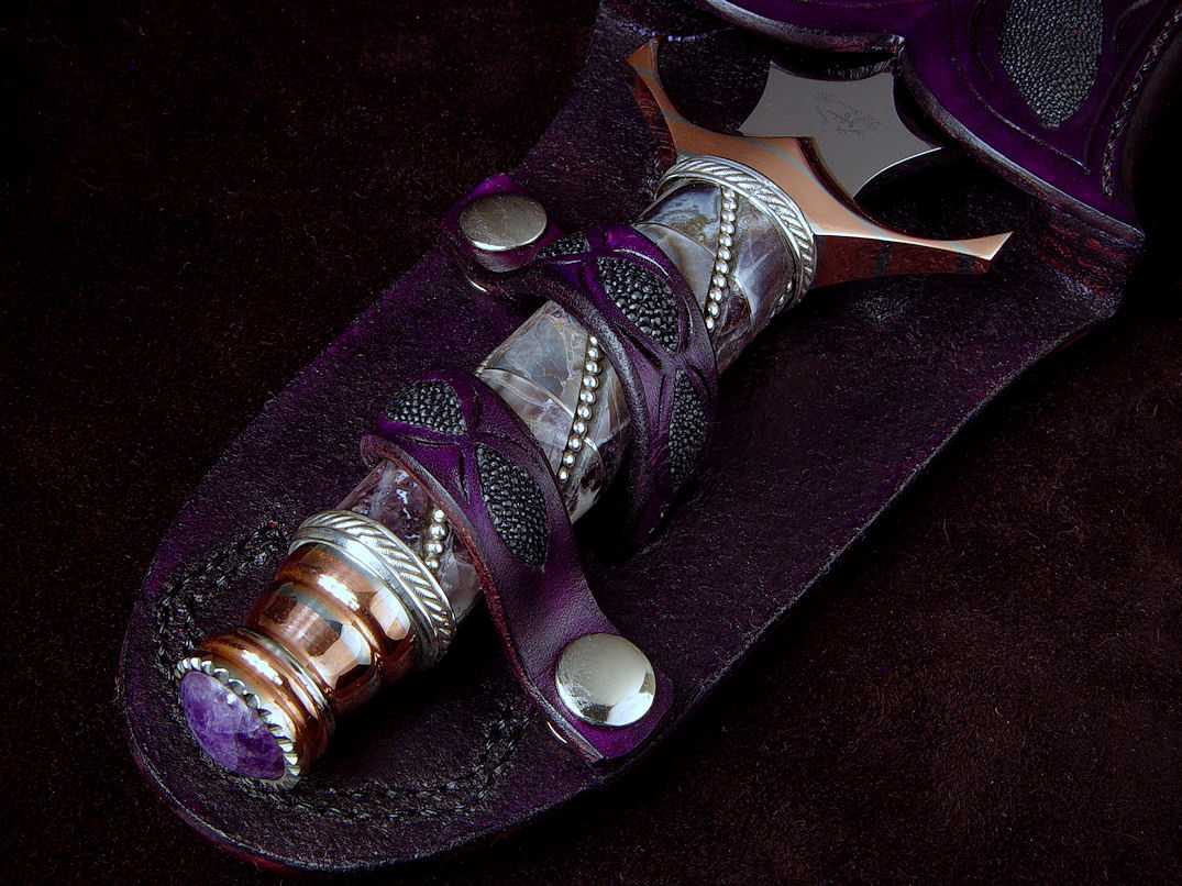 "Amethistine" dagger, obverse side view in 440C high chromium stainless steel blade, diffusion welded copper, nickel silver fittings, sterling silver gallery wire wrap and accents, Amethyst crystal gemstone pommel, hand-carved leather sheath inlaid with black rayskin