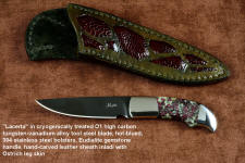 "Lacerta" obverse side view, in deep cryogenically treated O1 tungsten-vanadium tool steel blade, hot blued, 304 stainless steel bolsters, Eudialite gemstone handle, sheath of hand-carved leather inlaid with Ostrich leg skin